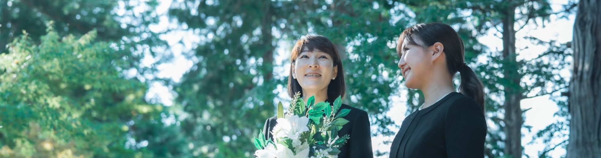 花束を持つ喪服の女性たち