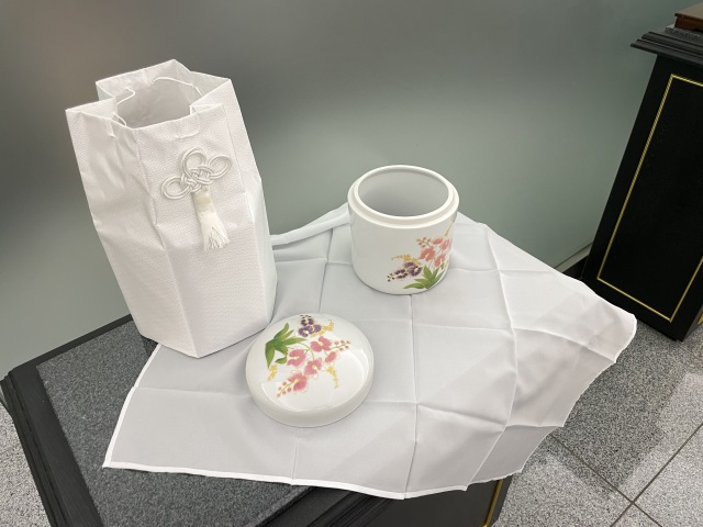 白い布の上に置かれた骨壺と袋