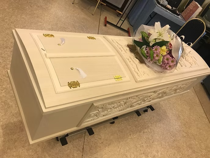 白い棺の上に置かれた花